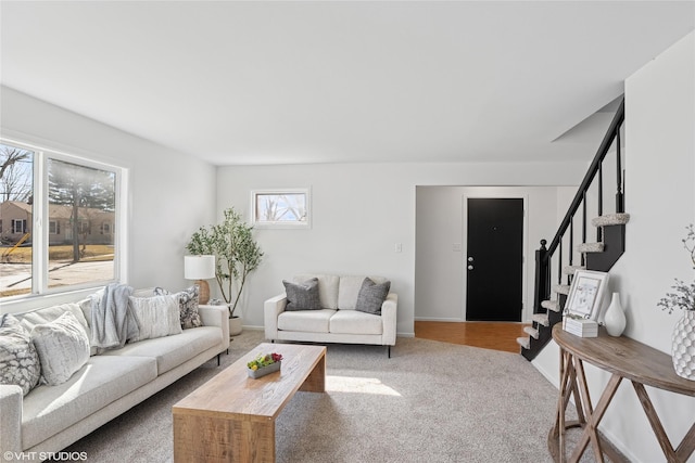 carpeted living area featuring baseboards and stairs