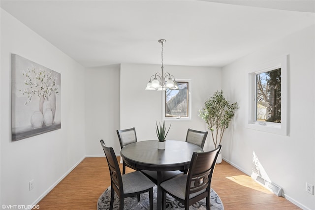 dining room with baseboards, light wood-type flooring, and an inviting chandelier