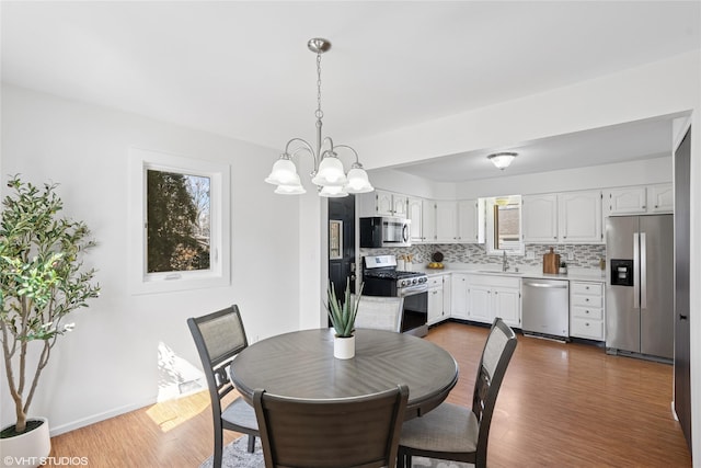 dining area with plenty of natural light, baseboards, dark wood-type flooring, and an inviting chandelier