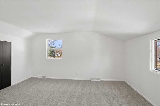 interior space featuring lofted ceiling, multiple windows, visible vents, and carpet floors