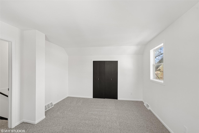 unfurnished room featuring vaulted ceiling, visible vents, baseboards, and carpet floors