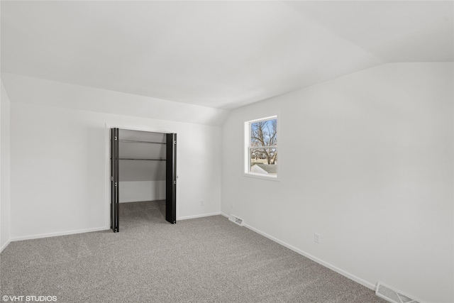 unfurnished bedroom featuring lofted ceiling, carpet, and visible vents