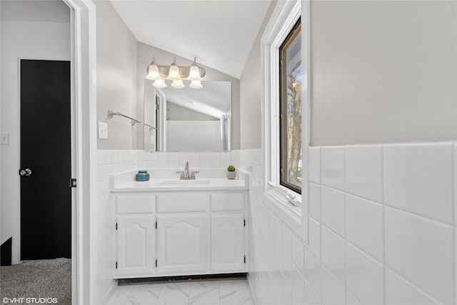 bathroom with an inviting chandelier, vaulted ceiling, vanity, and tile walls