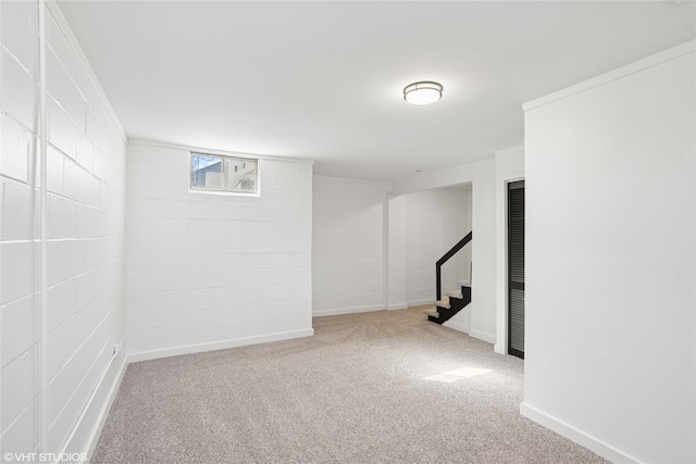 basement featuring carpet flooring, stairway, concrete block wall, and baseboards