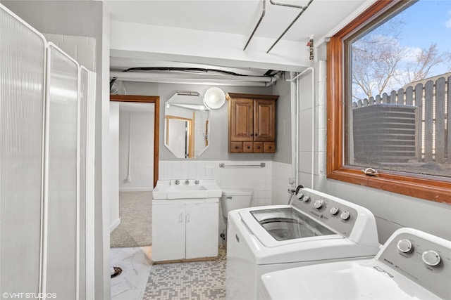 washroom featuring laundry area, a sink, washer and dryer, tile walls, and marble finish floor