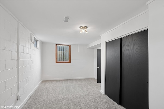 basement featuring visible vents, carpet floors, and concrete block wall