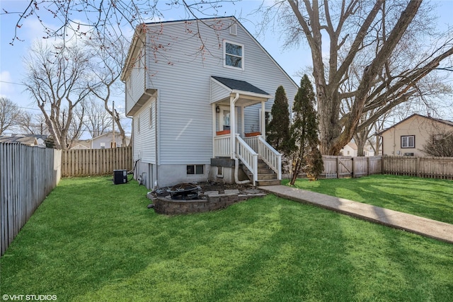 rear view of property with a fire pit, a lawn, and a fenced backyard