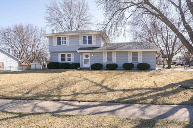 view of front of house with a chimney, a front yard, and fence