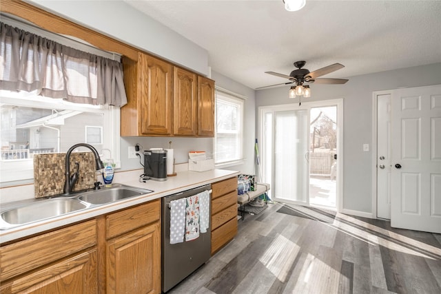 kitchen with a ceiling fan, a sink, stainless steel dishwasher, light wood-style floors, and light countertops