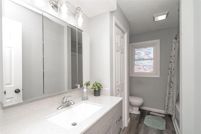 bathroom with a textured ceiling, toilet, vanity, and wood finished floors