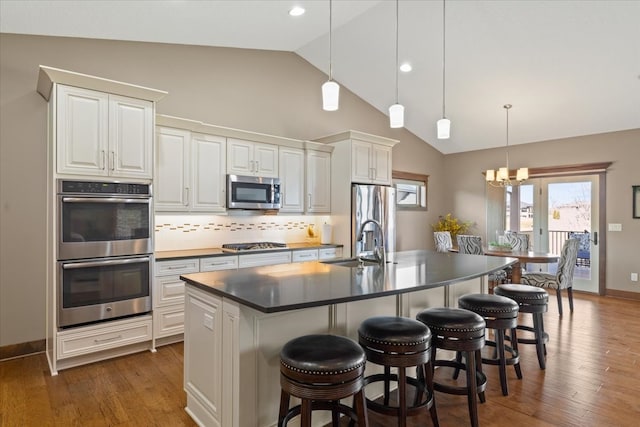 kitchen with dark wood-style floors, appliances with stainless steel finishes, a kitchen bar, and a sink