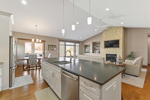 kitchen featuring a sink, dark countertops, open floor plan, and stainless steel appliances