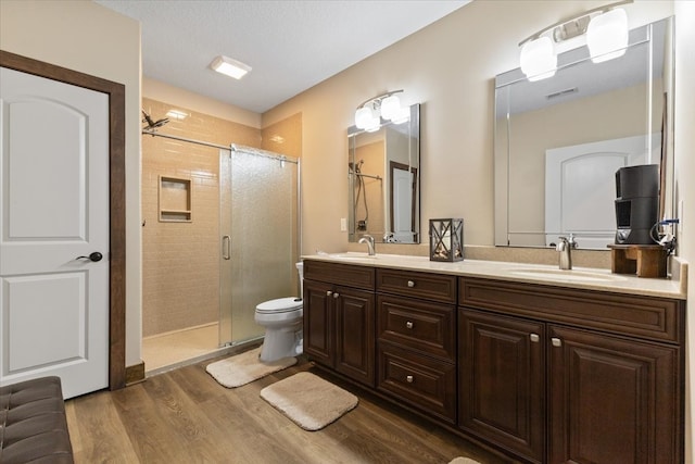 full bath featuring a sink, visible vents, wood finished floors, and a shower stall