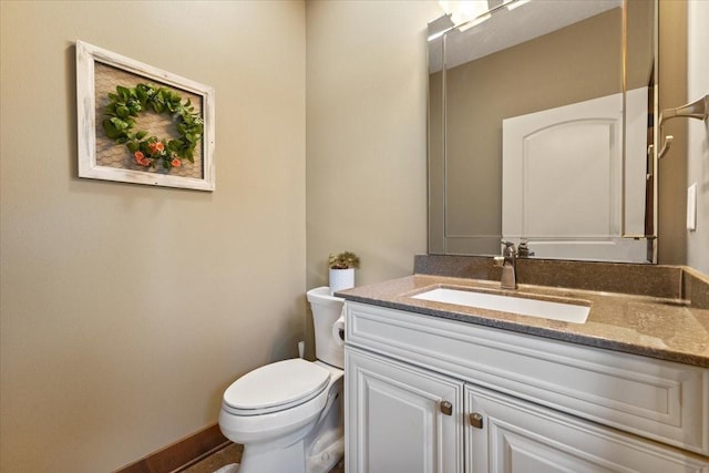 bathroom featuring toilet, vanity, and baseboards