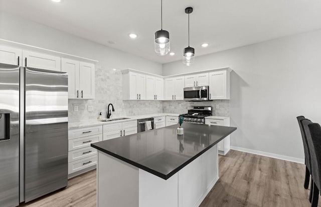 kitchen with a sink, stainless steel appliances, light wood-style floors, white cabinets, and decorative backsplash