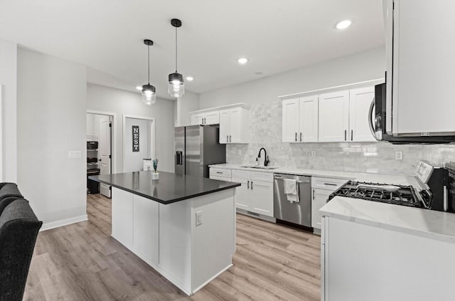 kitchen featuring tasteful backsplash, appliances with stainless steel finishes, light wood-style floors, white cabinetry, and a sink