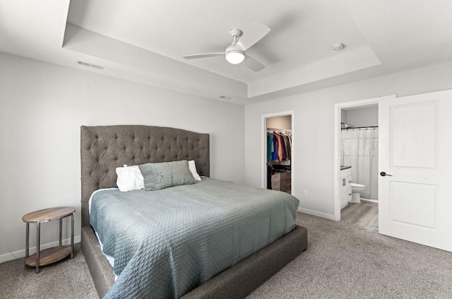 carpeted bedroom featuring a spacious closet, visible vents, baseboards, a tray ceiling, and a closet