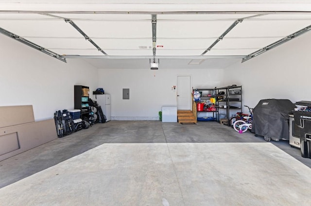 garage with electric panel, a garage door opener, and freestanding refrigerator