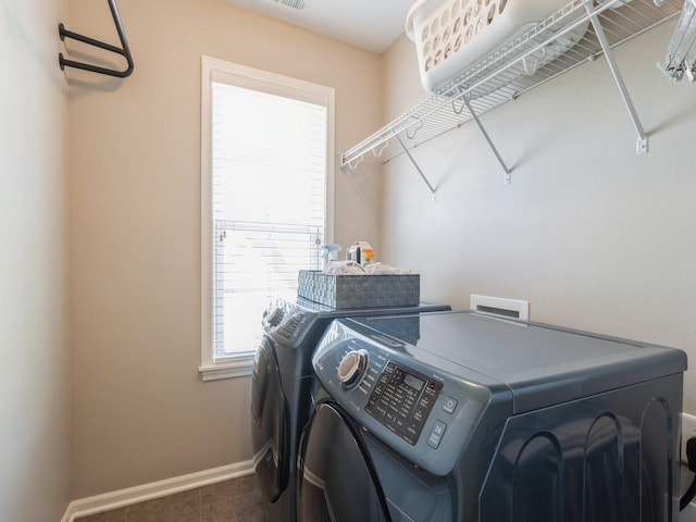 clothes washing area featuring tile patterned flooring, laundry area, baseboards, and washing machine and clothes dryer