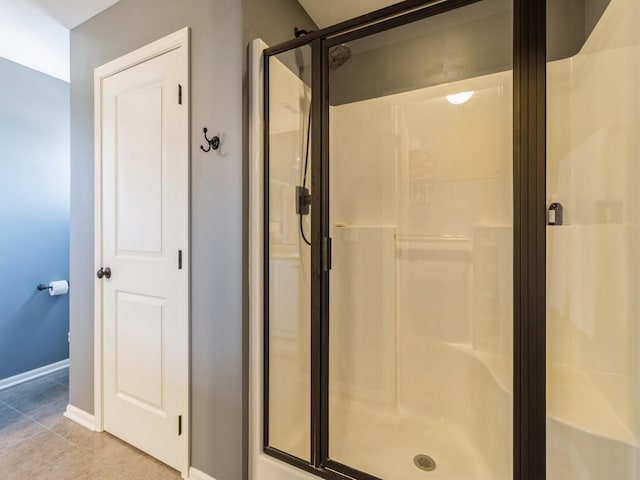 bathroom featuring tile patterned flooring, a shower stall, and baseboards