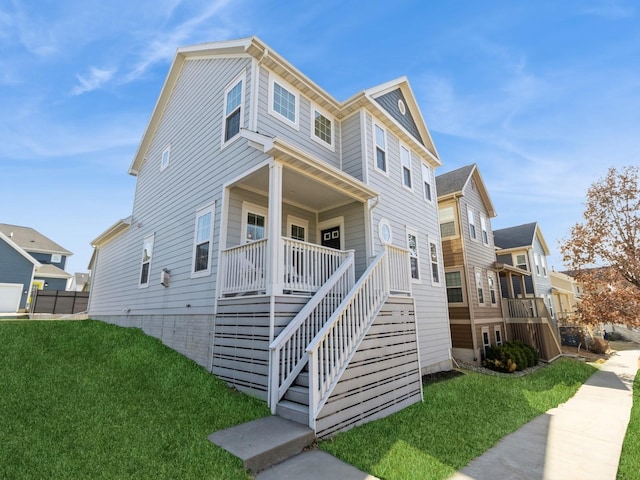 view of side of property with stairway, a lawn, and covered porch