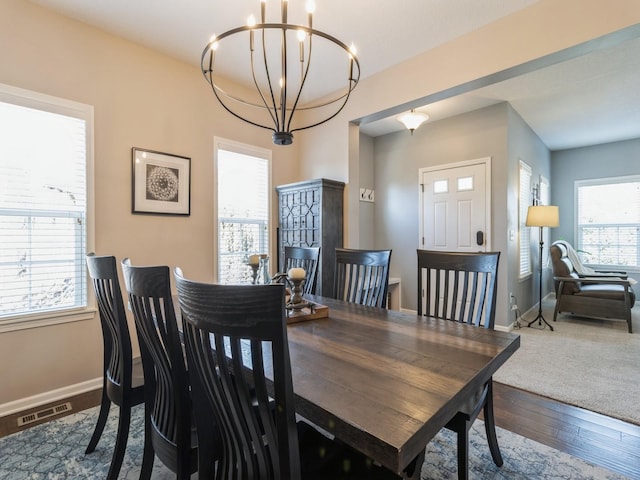 dining space featuring visible vents, baseboards, an inviting chandelier, and hardwood / wood-style flooring