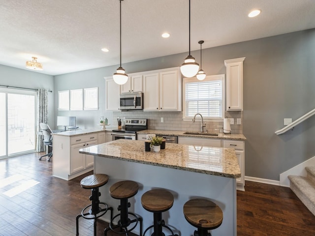 kitchen with a sink, a center island, stainless steel appliances, a peninsula, and decorative backsplash