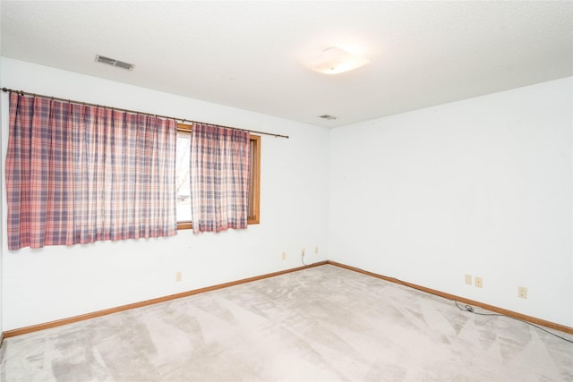 carpeted empty room featuring baseboards, visible vents, and a textured ceiling