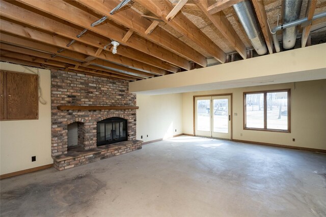 unfurnished living room featuring unfinished concrete floors, baseboards, and a brick fireplace