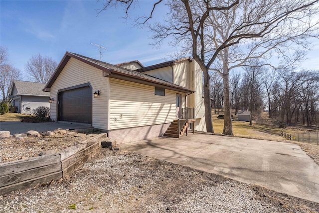 view of side of home featuring concrete driveway and an attached garage