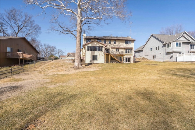 rear view of house featuring a wooden deck, a yard, and fence