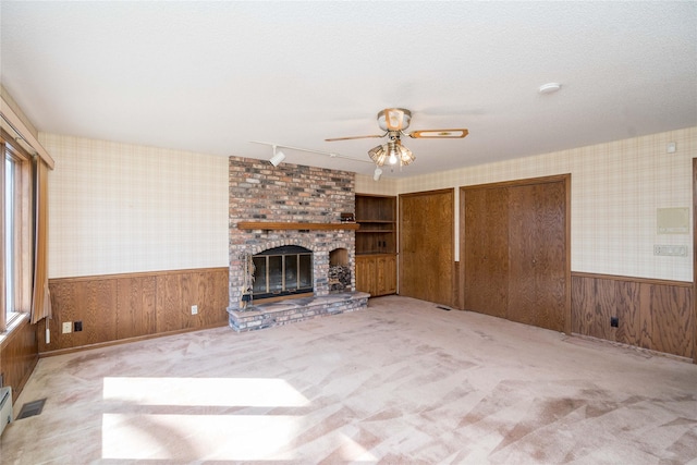 unfurnished living room with wainscoting, wallpapered walls, a ceiling fan, and carpet floors