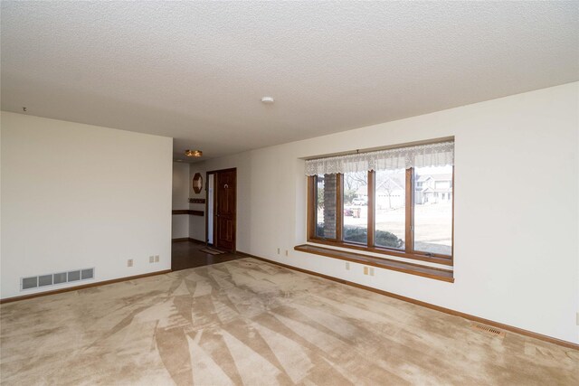 unfurnished room featuring visible vents, baseboards, a textured ceiling, and carpet flooring