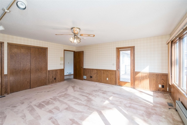 unfurnished bedroom featuring a wainscoted wall, multiple windows, and wallpapered walls