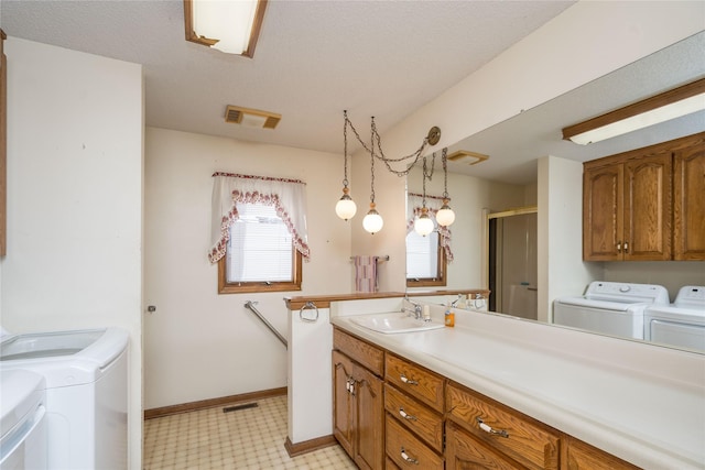 clothes washing area featuring visible vents, light floors, laundry area, independent washer and dryer, and a sink