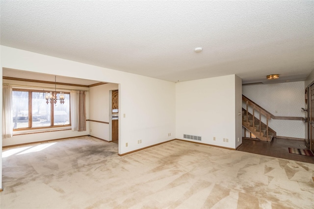 spare room with carpet, visible vents, stairs, a textured ceiling, and a chandelier