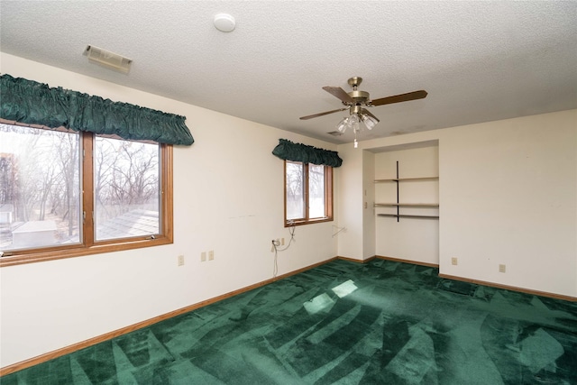 empty room with a ceiling fan, visible vents, baseboards, a textured ceiling, and dark colored carpet