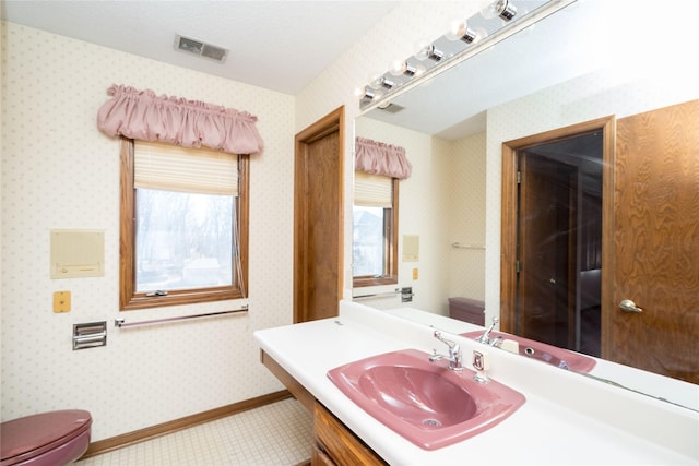 half bathroom with visible vents, toilet, wallpapered walls, and baseboards