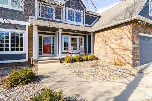 property entrance featuring a porch, an attached garage, stone siding, and a shingled roof