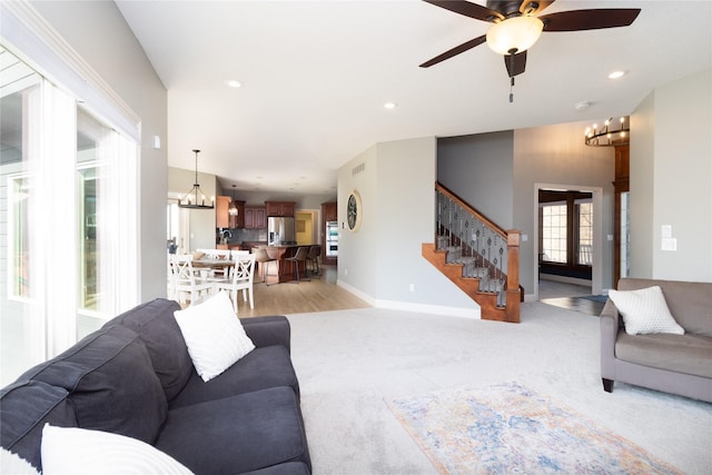 living area featuring recessed lighting, ceiling fan with notable chandelier, stairs, and baseboards