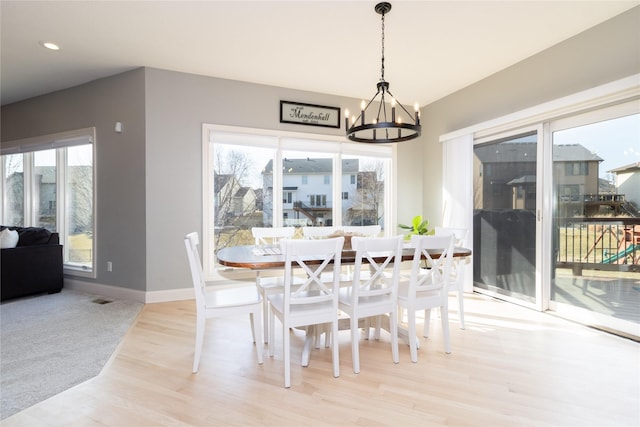 dining space featuring an inviting chandelier, plenty of natural light, wood finished floors, and baseboards