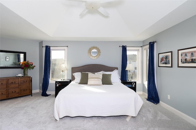 bedroom with a ceiling fan, baseboards, lofted ceiling, a tray ceiling, and carpet flooring