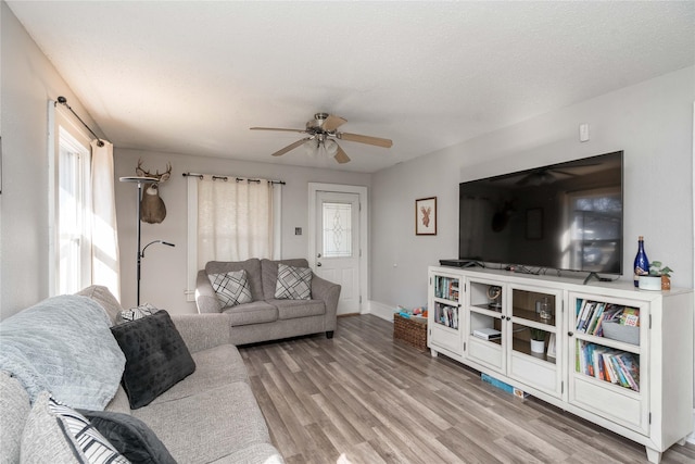 living room with wood finished floors, a ceiling fan, and a wealth of natural light