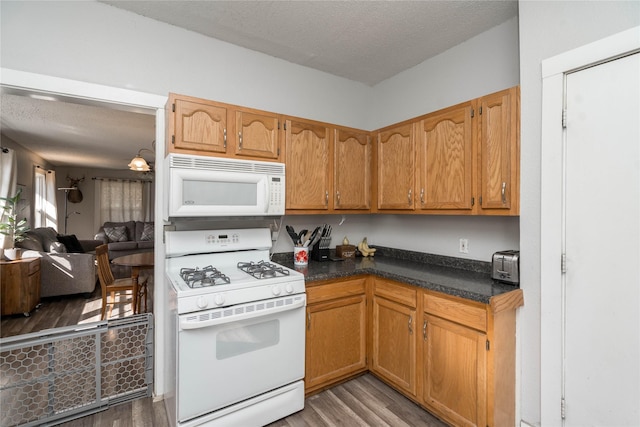 kitchen featuring white appliances, dark countertops, light wood finished floors, and a textured ceiling