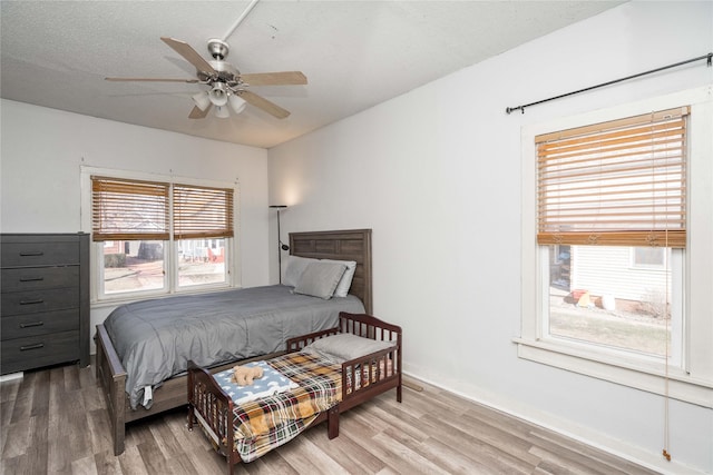 bedroom featuring ceiling fan, wood finished floors, baseboards, and a textured ceiling