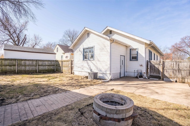 back of property featuring fence, an outdoor fire pit, central AC unit, a patio, and a gate