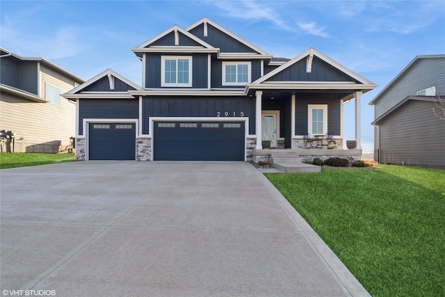 craftsman-style house with a front lawn, stone siding, a porch, board and batten siding, and an attached garage