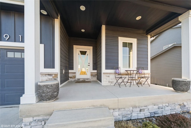 entrance to property with a garage, covered porch, and stone siding