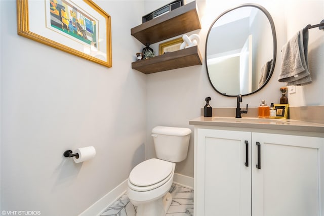 half bathroom with baseboards, toilet, marble finish floor, and vanity