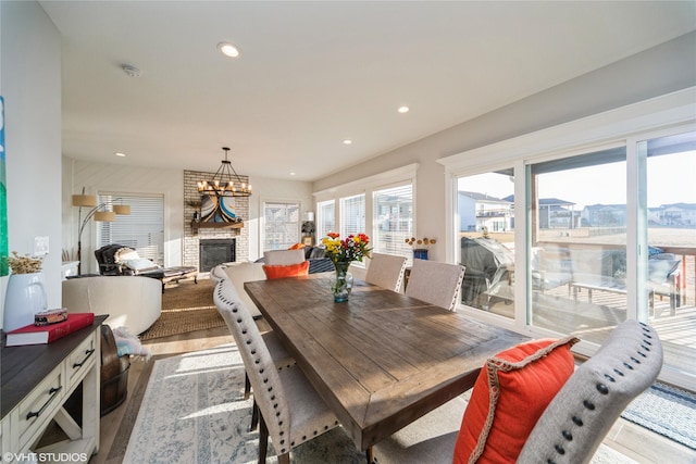 dining area featuring recessed lighting, a chandelier, a fireplace, and light wood finished floors